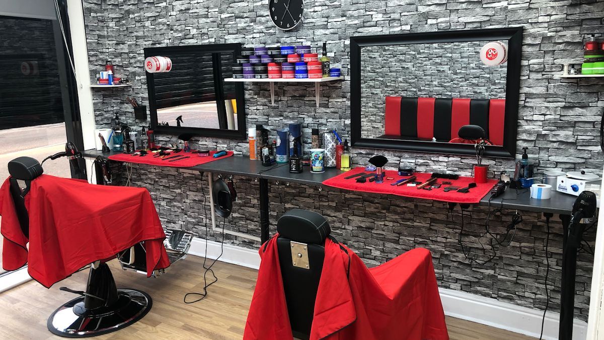 The stations at Cleancut barber shop, mirrors and products along a grey stone-effect wall