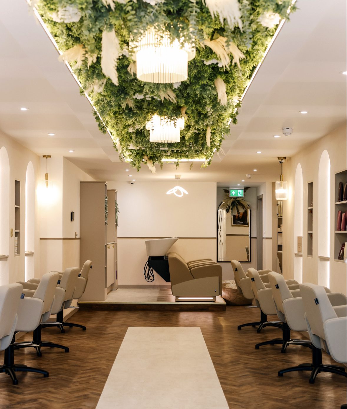 Inside Elysium Salon, styling chairs down both sides beneath a flower installation