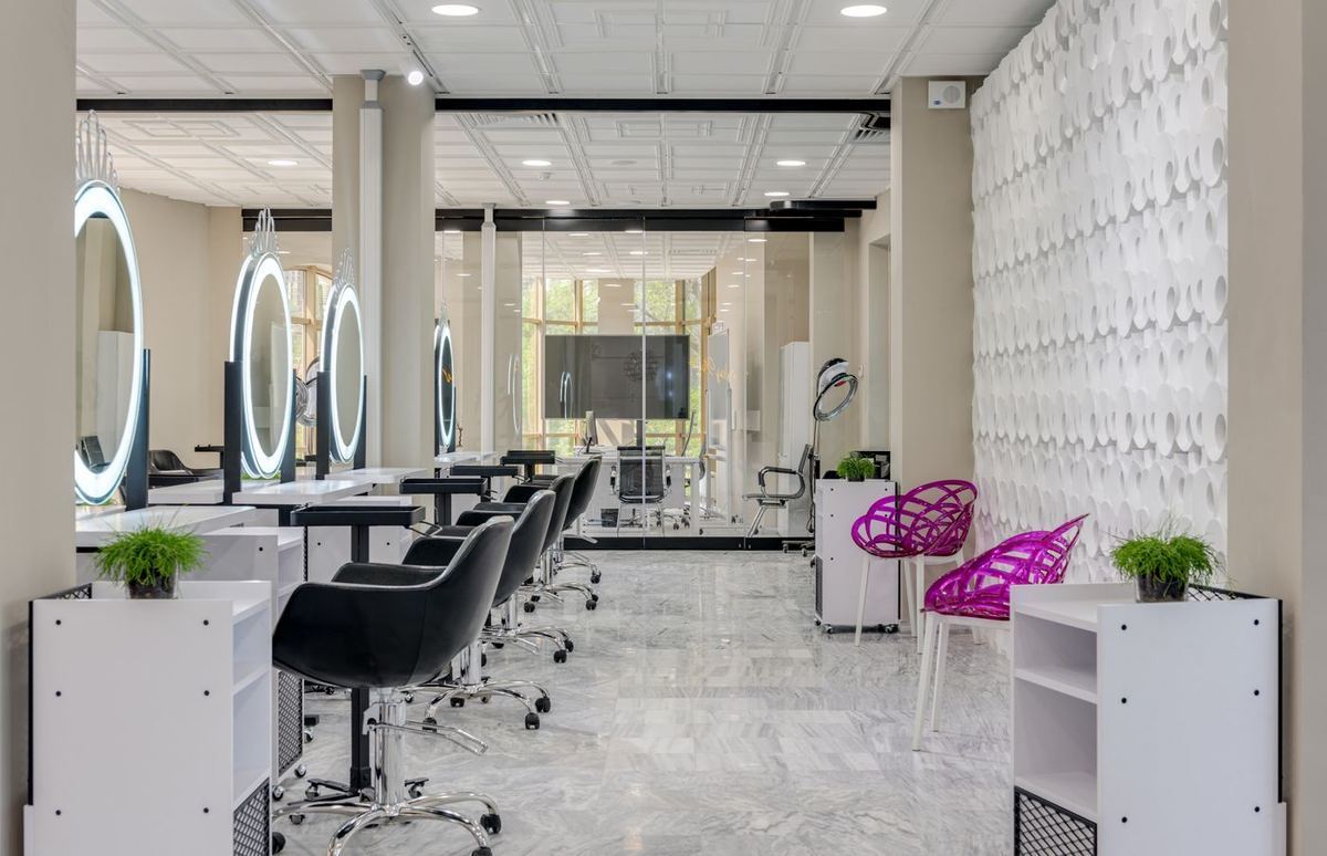 A salon interior with styling chairs and lit vanity mirrors