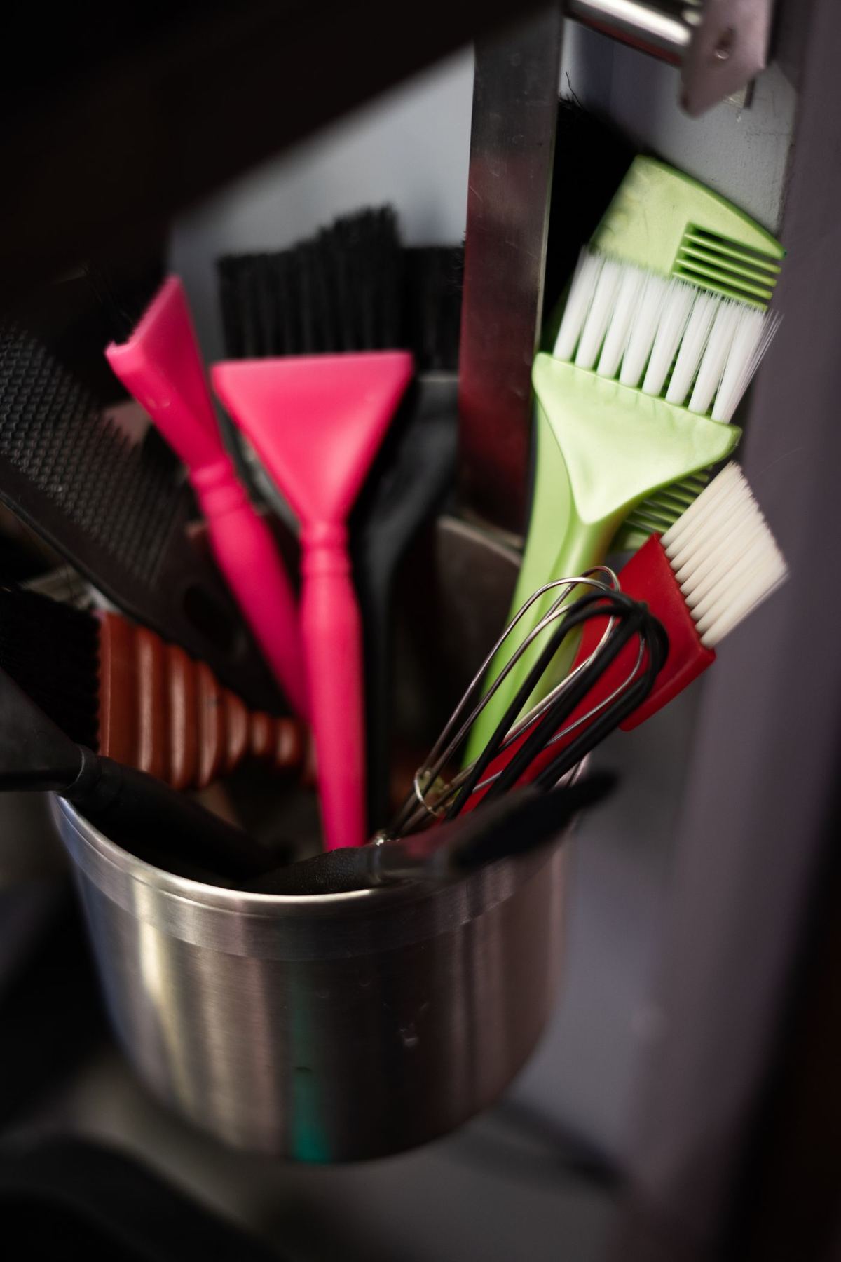 Brushes and styling tools in a metal pot on a salon counter