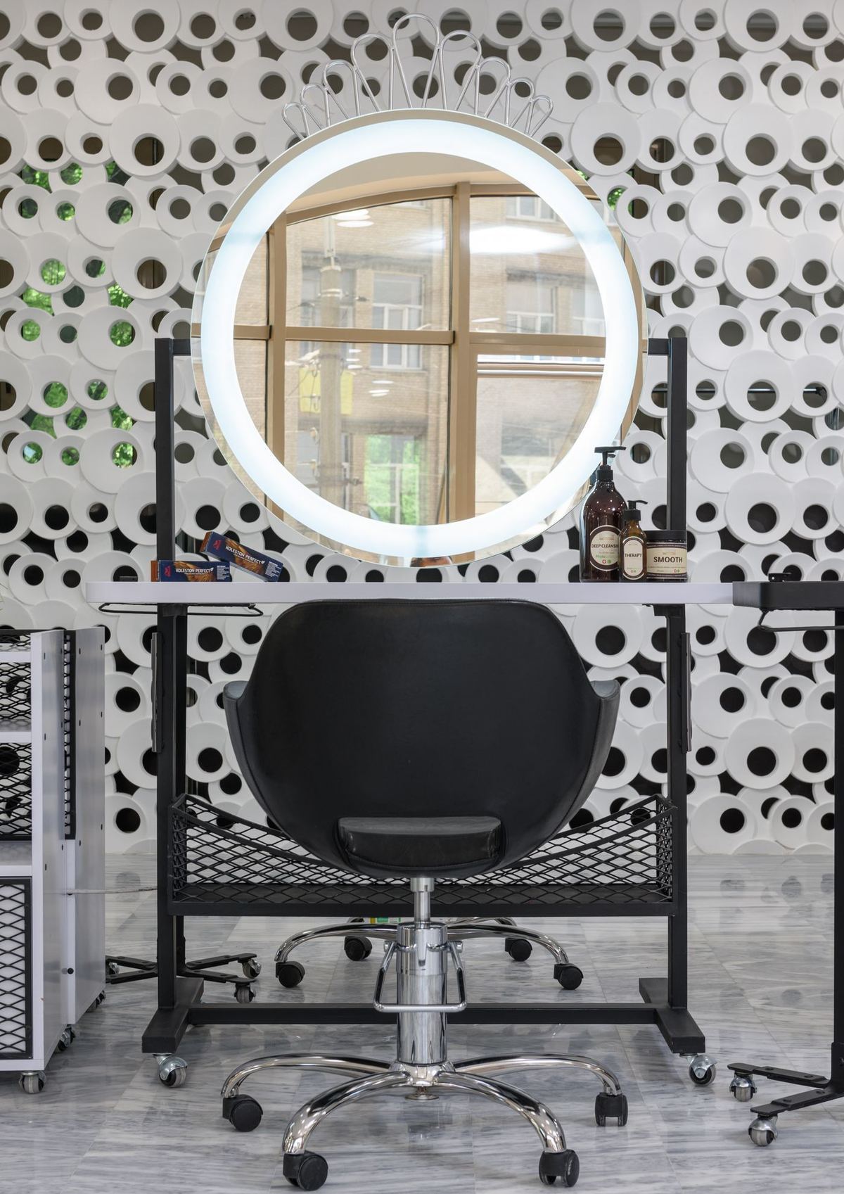 A styling station with a lit mirror and a chair