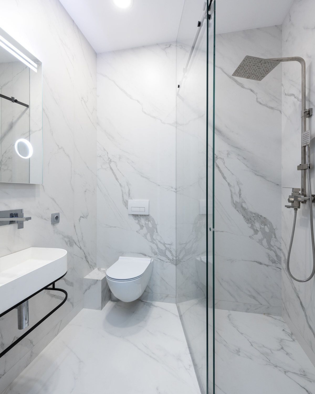 A marble-tiled walk-in shower with a wall-hung toilet