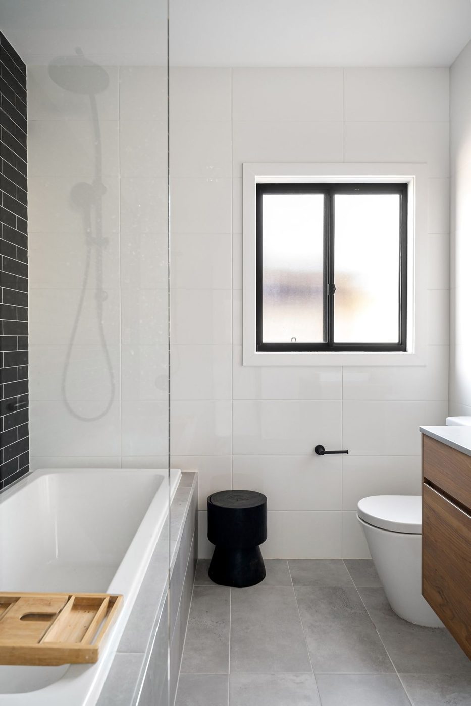 A white bathroom with black fittings, bath and shower