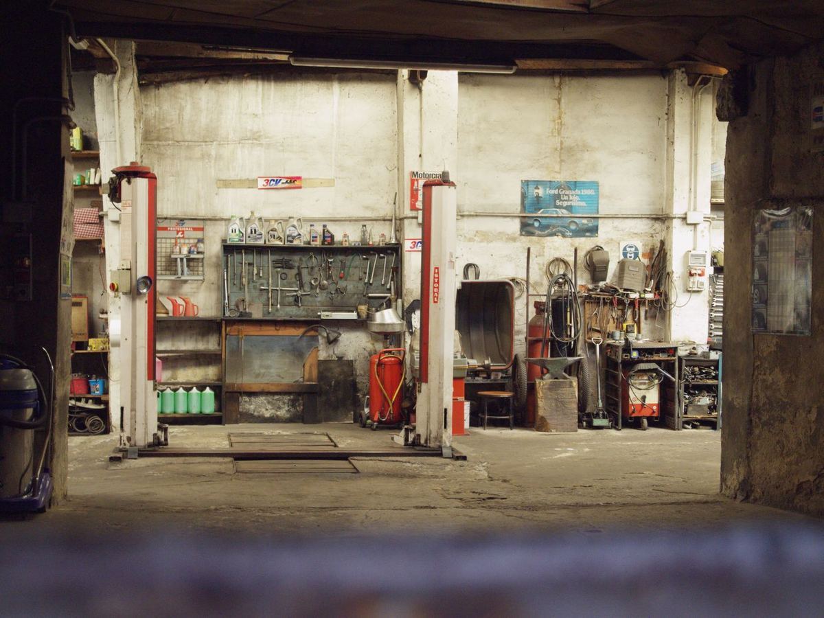 A garage bay with tools on the wall and a two-post lift