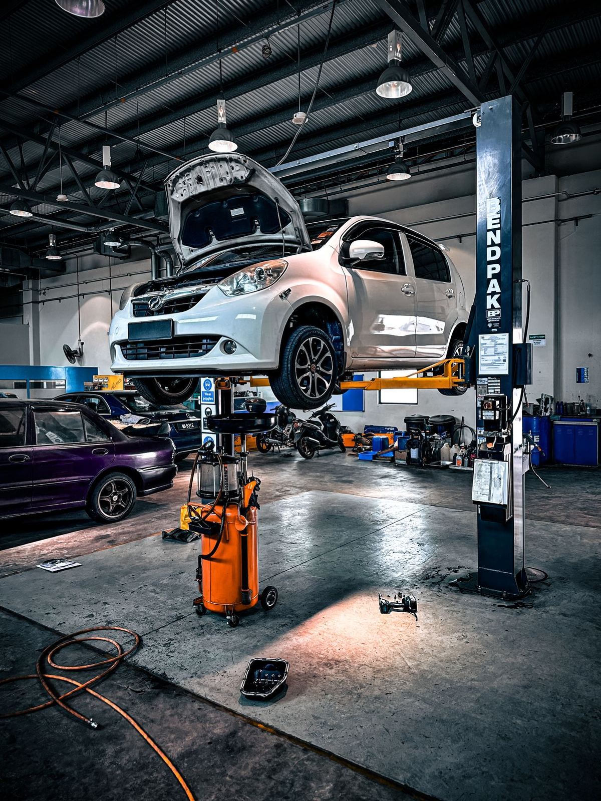 A car raised on a two-post lift in a garage