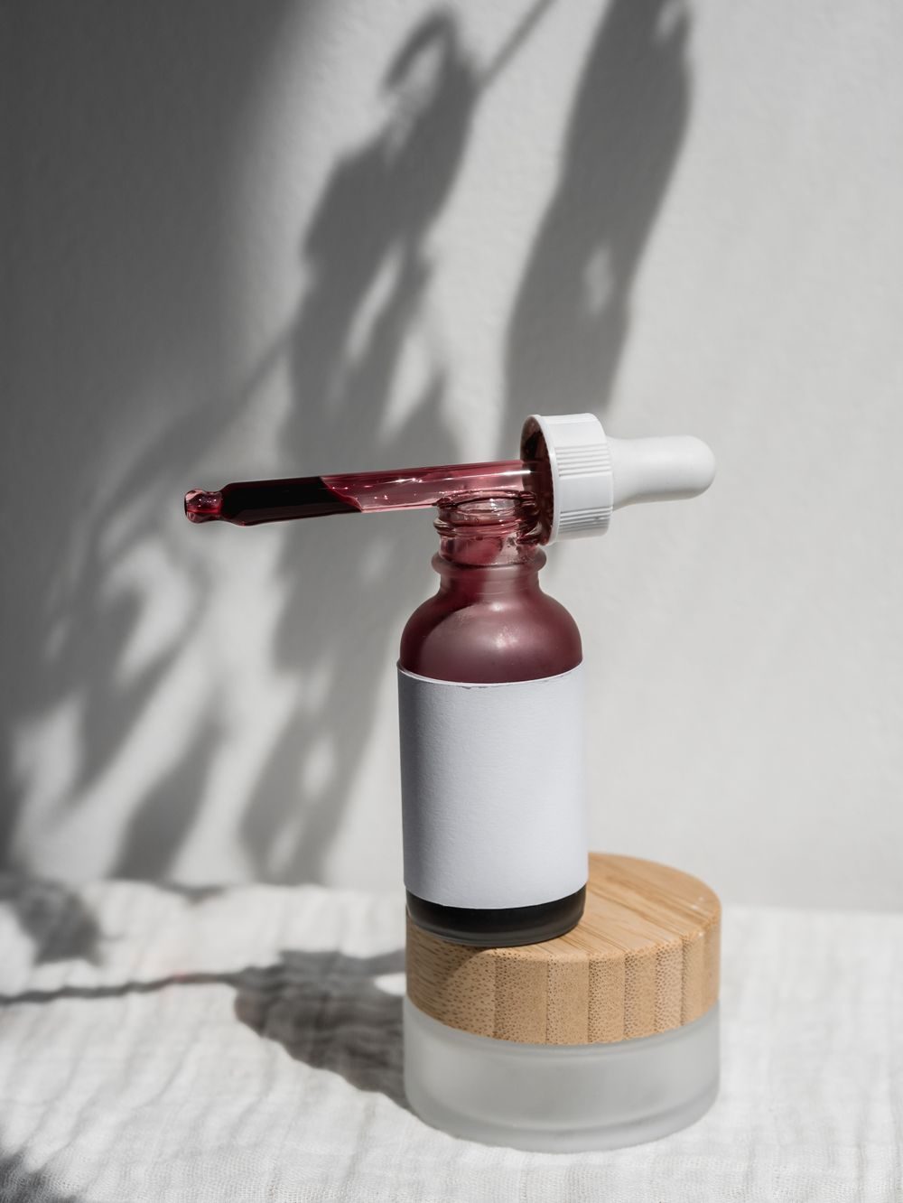 A serum dropper resting on a jar in afternoon light
