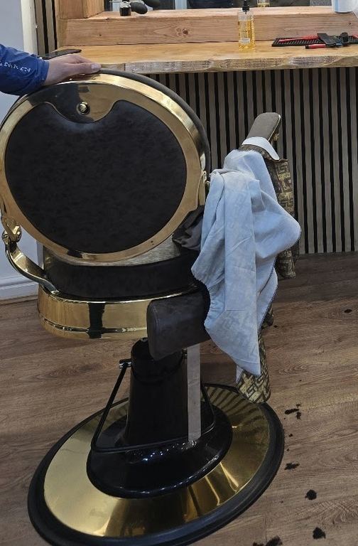 The back of a gold barber chair at Royal Barbers with a towel over the arm