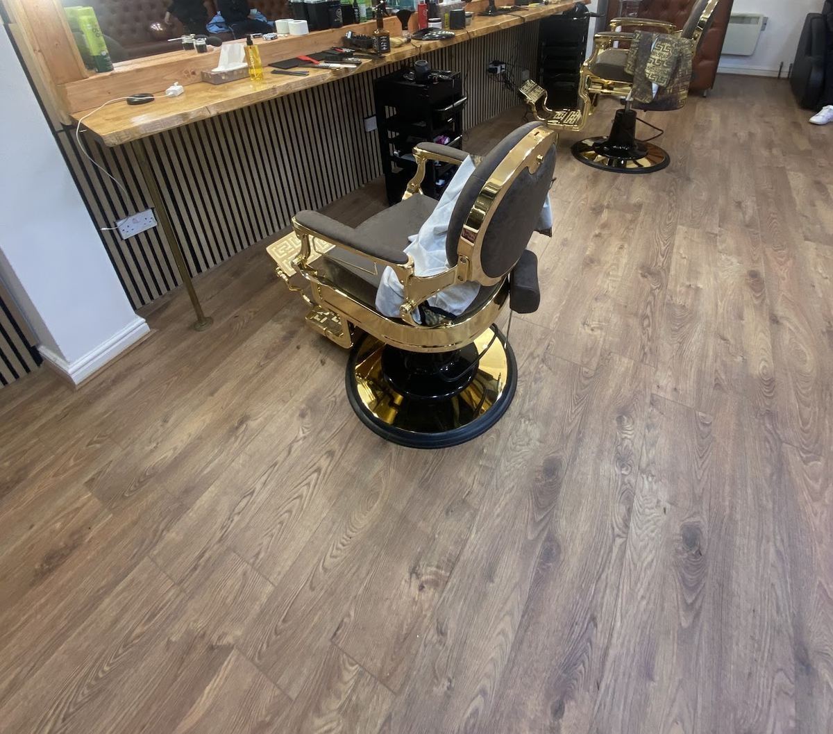 A gold and black barber chair on the wooden floor at Royal Barbers