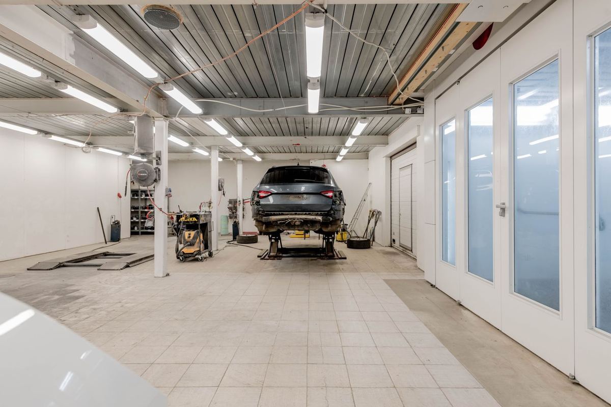 A bright garage workshop with a car raised on ramps