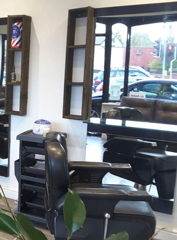 A black barber chair and mirrors by the window at Winton Barber